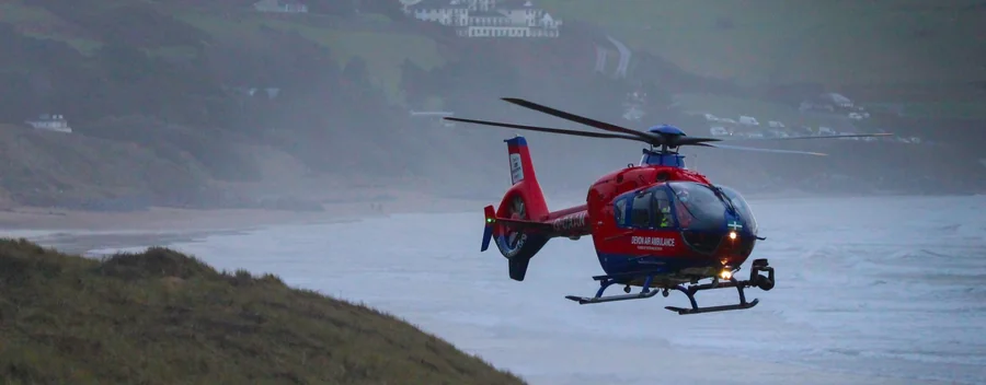 Devon Air Ambulance helicopter flying beside the Devon coast